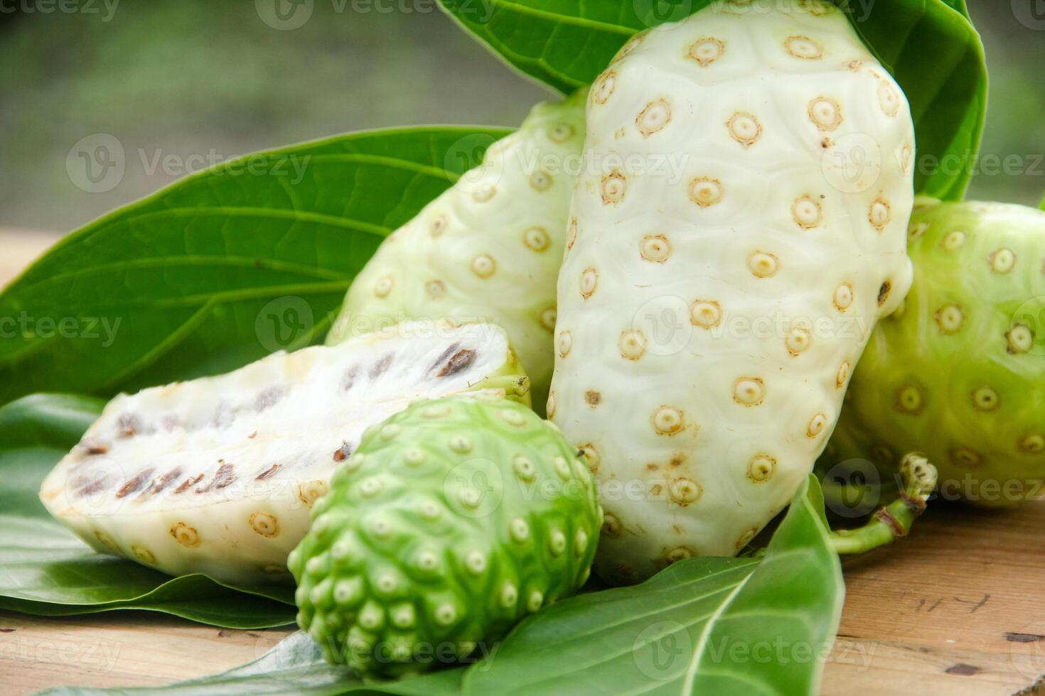 Noni fruit or Morinda citrifolia sliced and decorated with fruit and leaves on a natural background photo