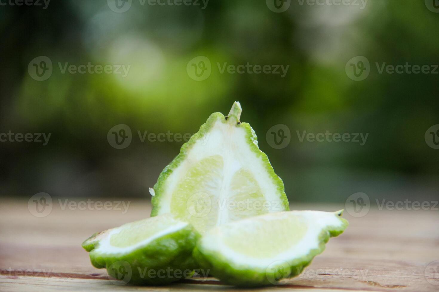 Bergamot fruits or sliced kaffir lime on wooden table and natural green background photo