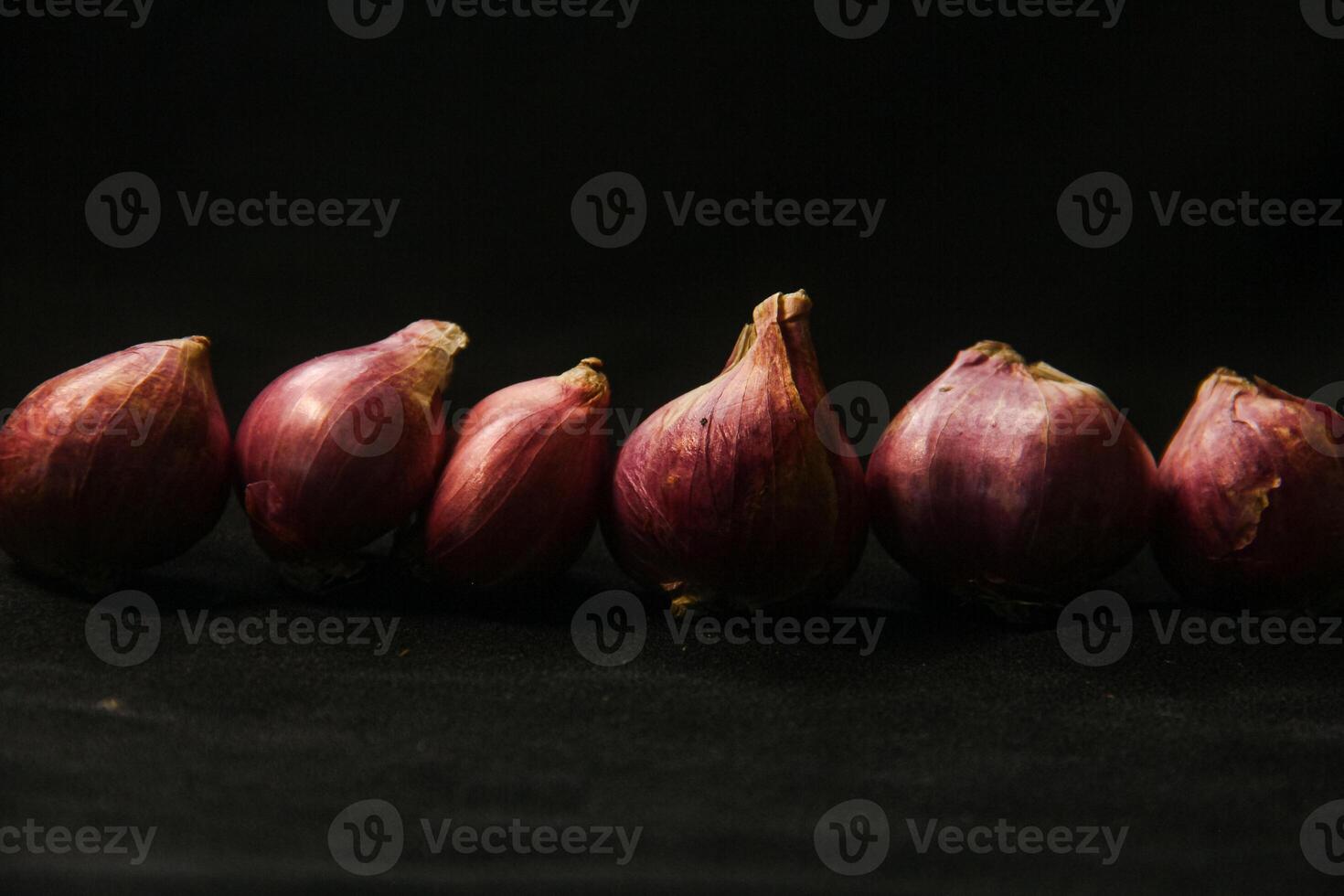 Close up of a whole red onion, isolated on a black background photo