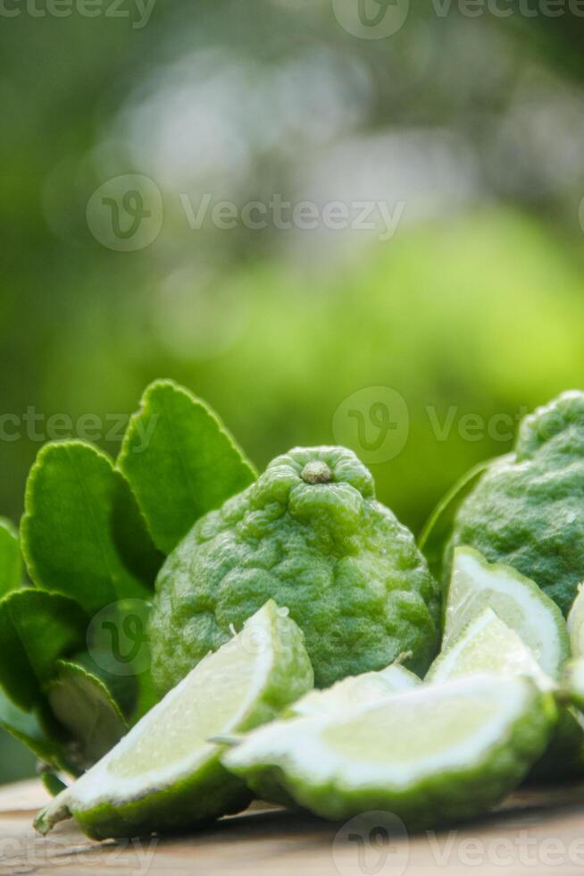 Bergamot fruits or sliced kaffir lime on wooden table and natural green background photo