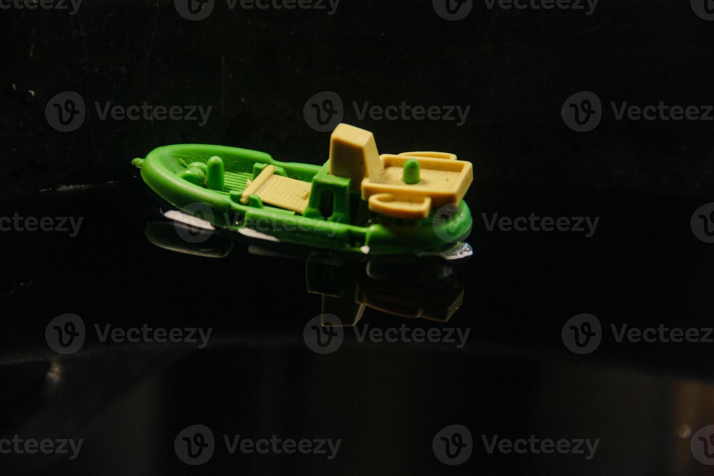 Miniature fishing boat made of plastic and sailing on dark water photo