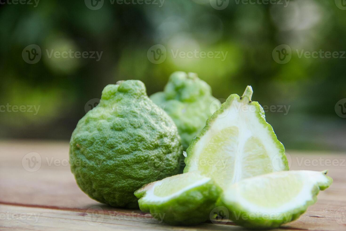 Bergamot fruits or sliced kaffir lime on wooden table and natural green background photo