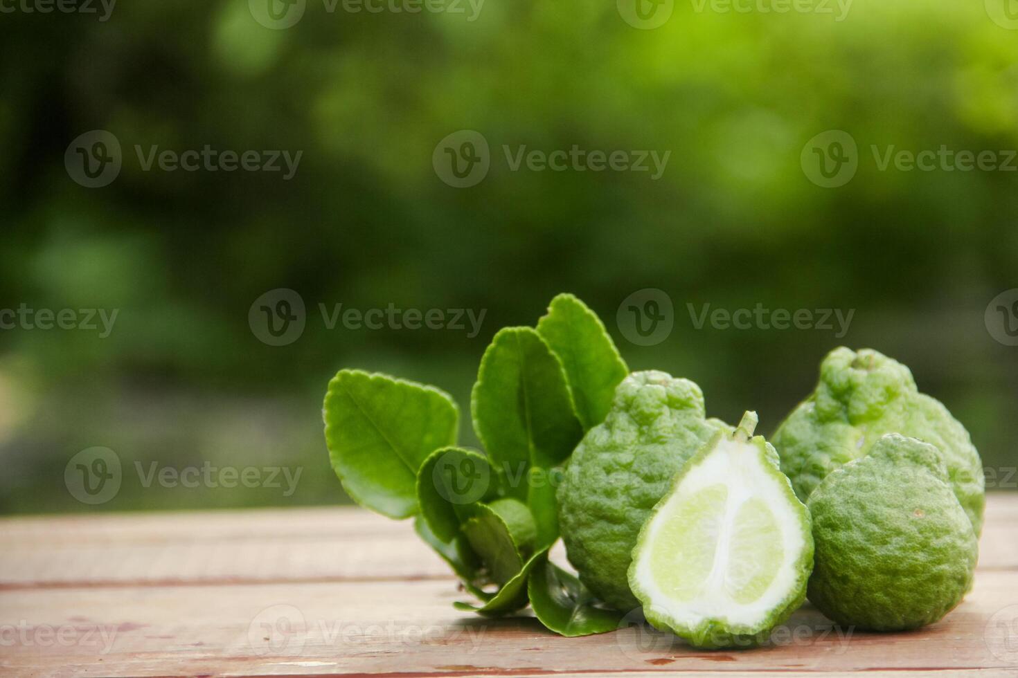 Bergamot fruits or sliced kaffir lime on wooden table and natural green background photo