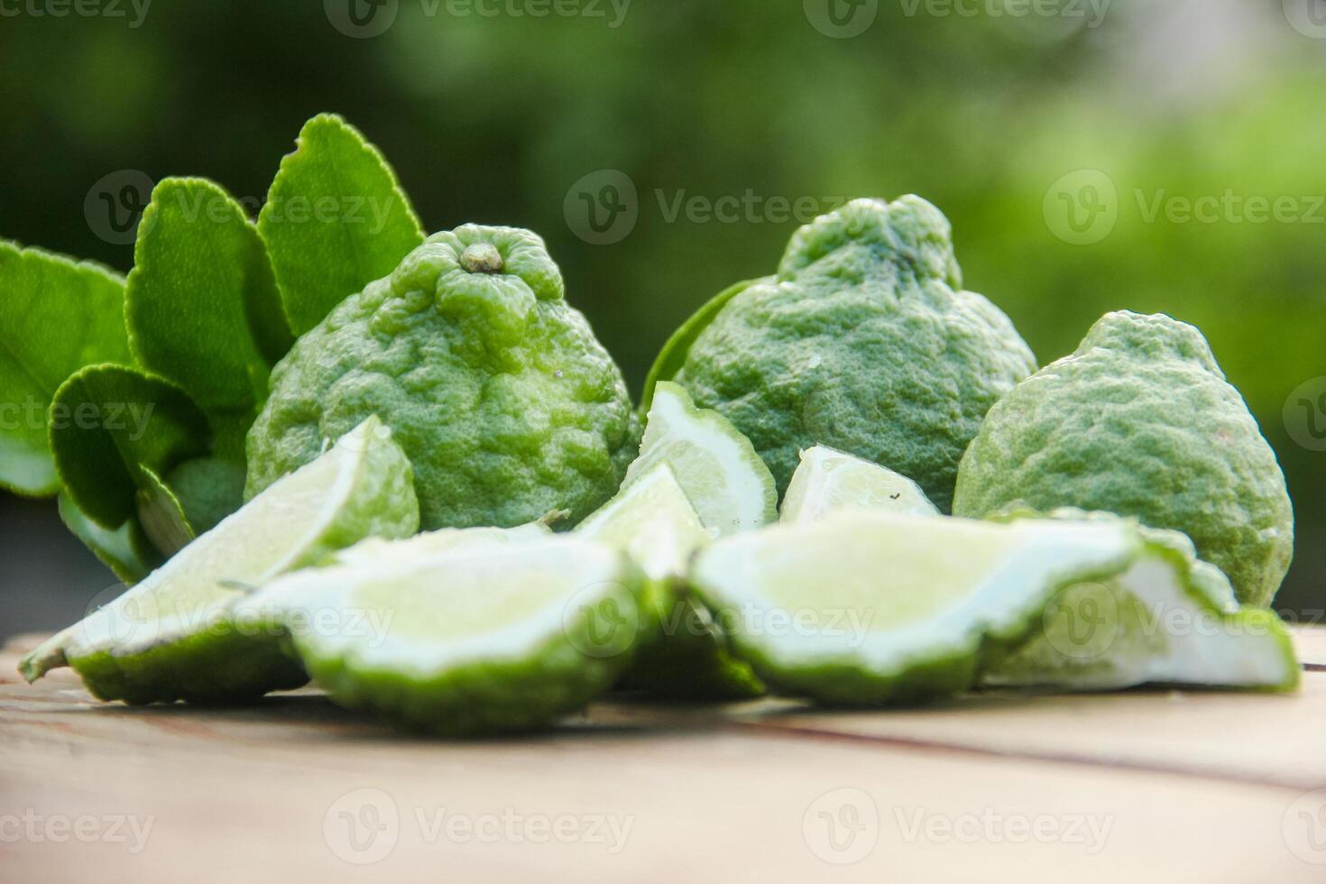 Bergamot fruits or sliced kaffir lime on wooden table and natural green background photo