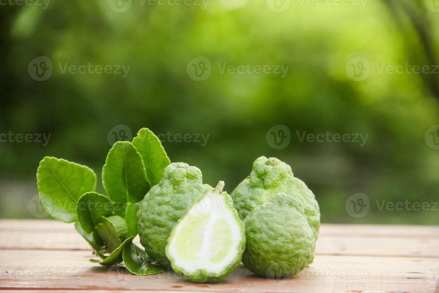 Bergamot fruits or sliced kaffir lime on wooden table and natural green background photo