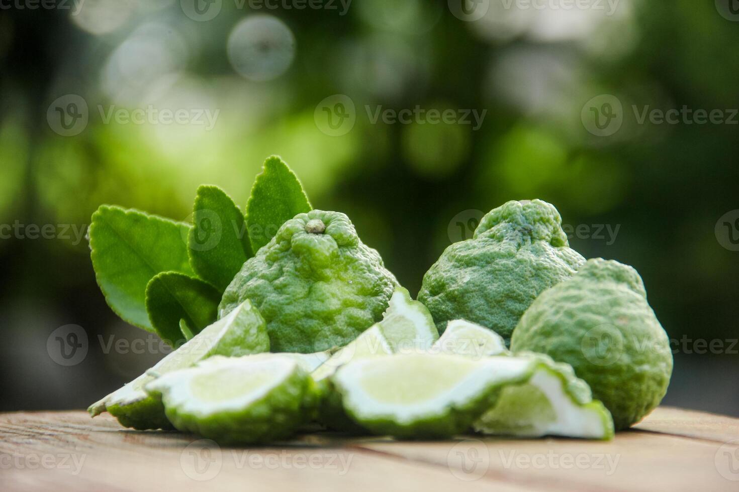 Bergamot fruits or sliced kaffir lime on wooden table and natural green background photo