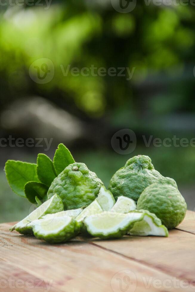 Bergamot fruits or sliced kaffir lime on wooden table and natural green background photo
