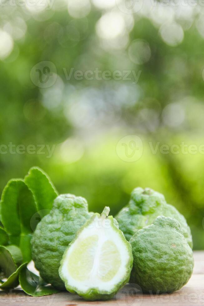 Bergamot fruits or sliced kaffir lime on wooden table and natural green background photo