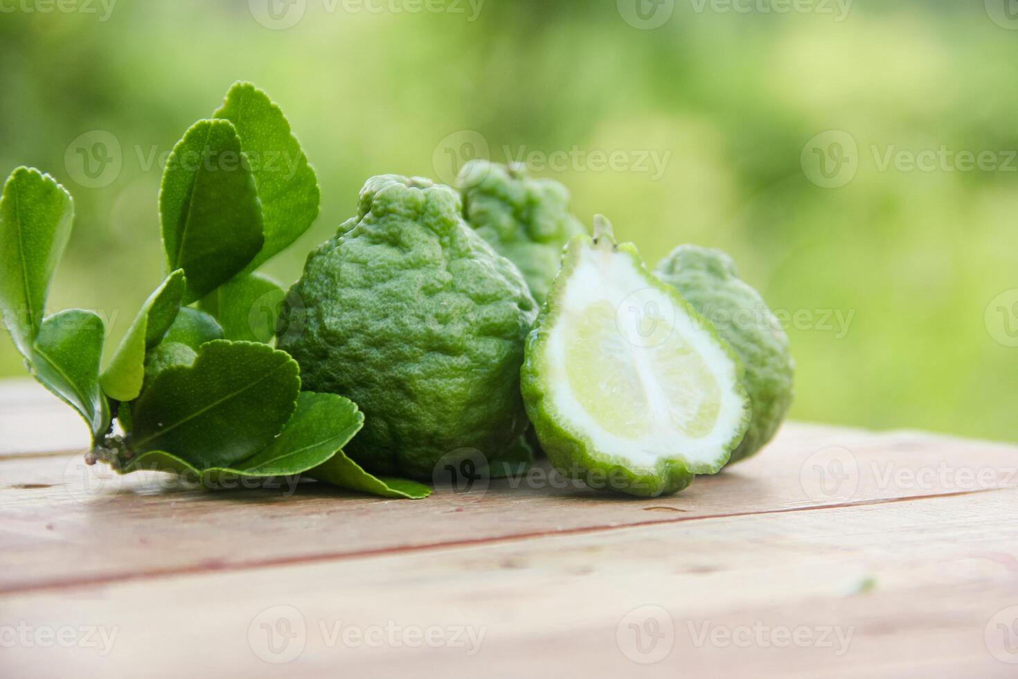 Bergamot fruits or sliced kaffir lime on wooden table and natural green background photo