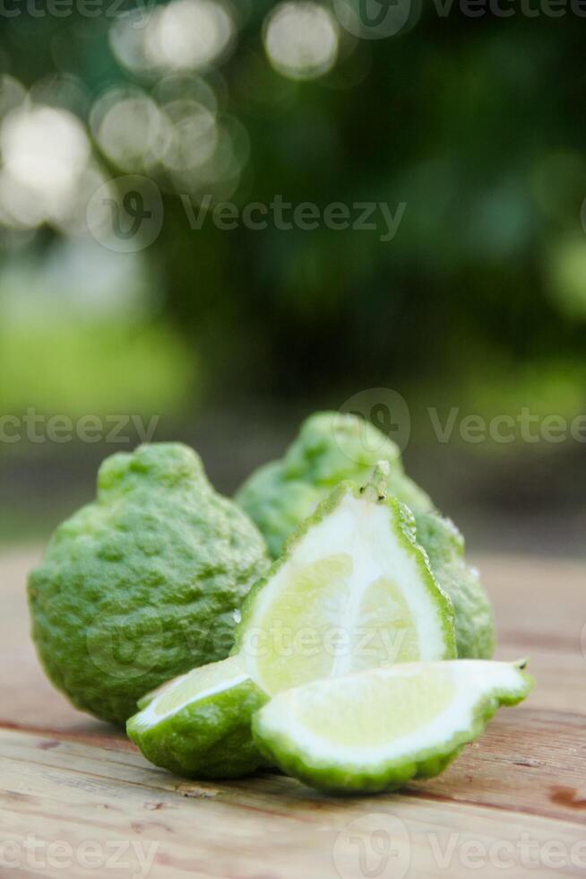 Bergamot fruits or sliced kaffir lime on wooden table and natural green background photo