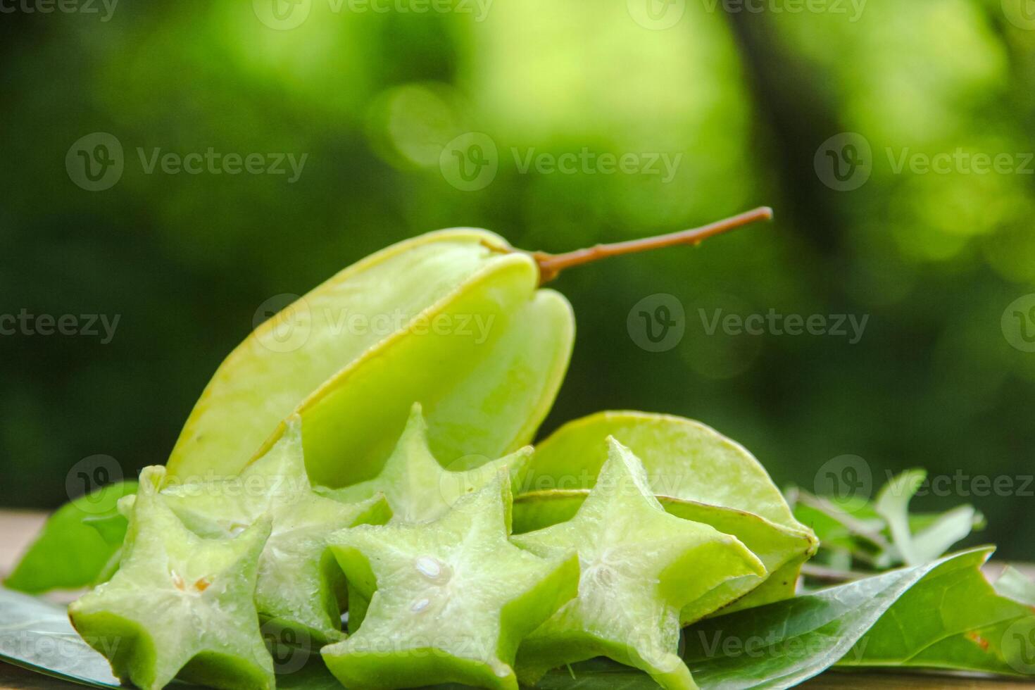 Carambola fruit with slice of star fruit on wooden table and natural background photo
