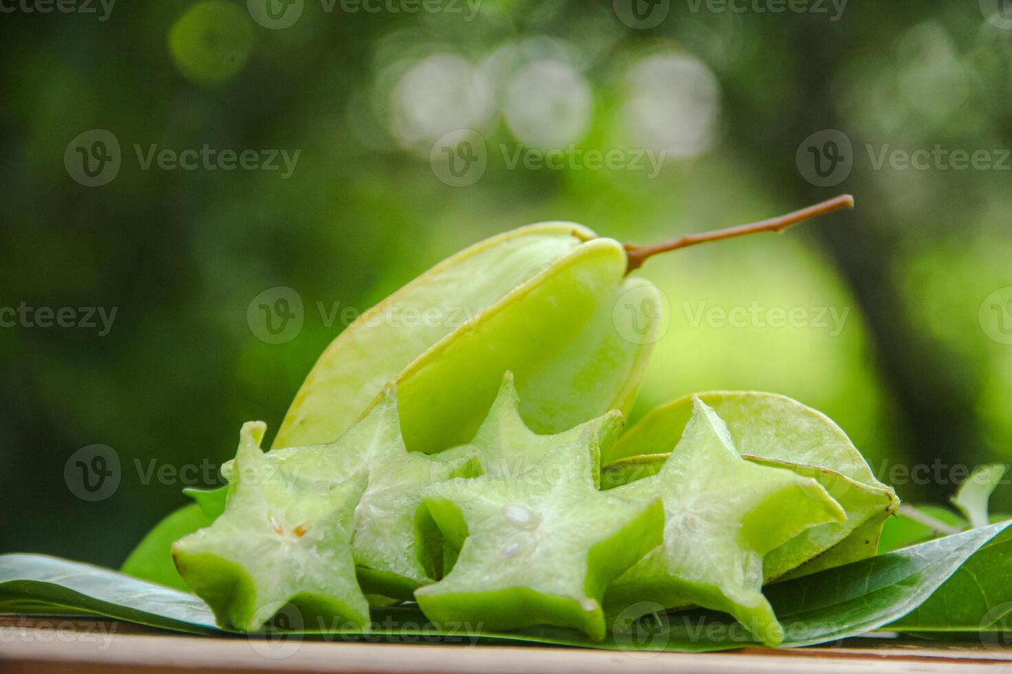 Carambola fruit with slice of star fruit on wooden table and natural background photo