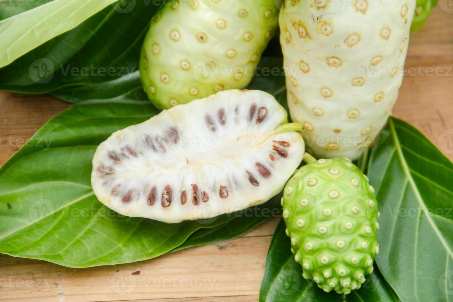 Noni fruit or Morinda citrifolia sliced and decorated with fruit and leaves on a natural background photo