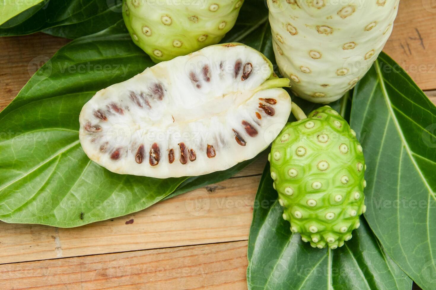 Noni fruit or Morinda citrifolia sliced and decorated with fruit and leaves on a natural background photo