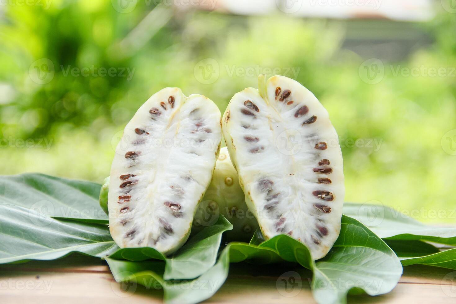 Noni fruit or Morinda citrifolia sliced and decorated with fruit and leaves on a natural background photo