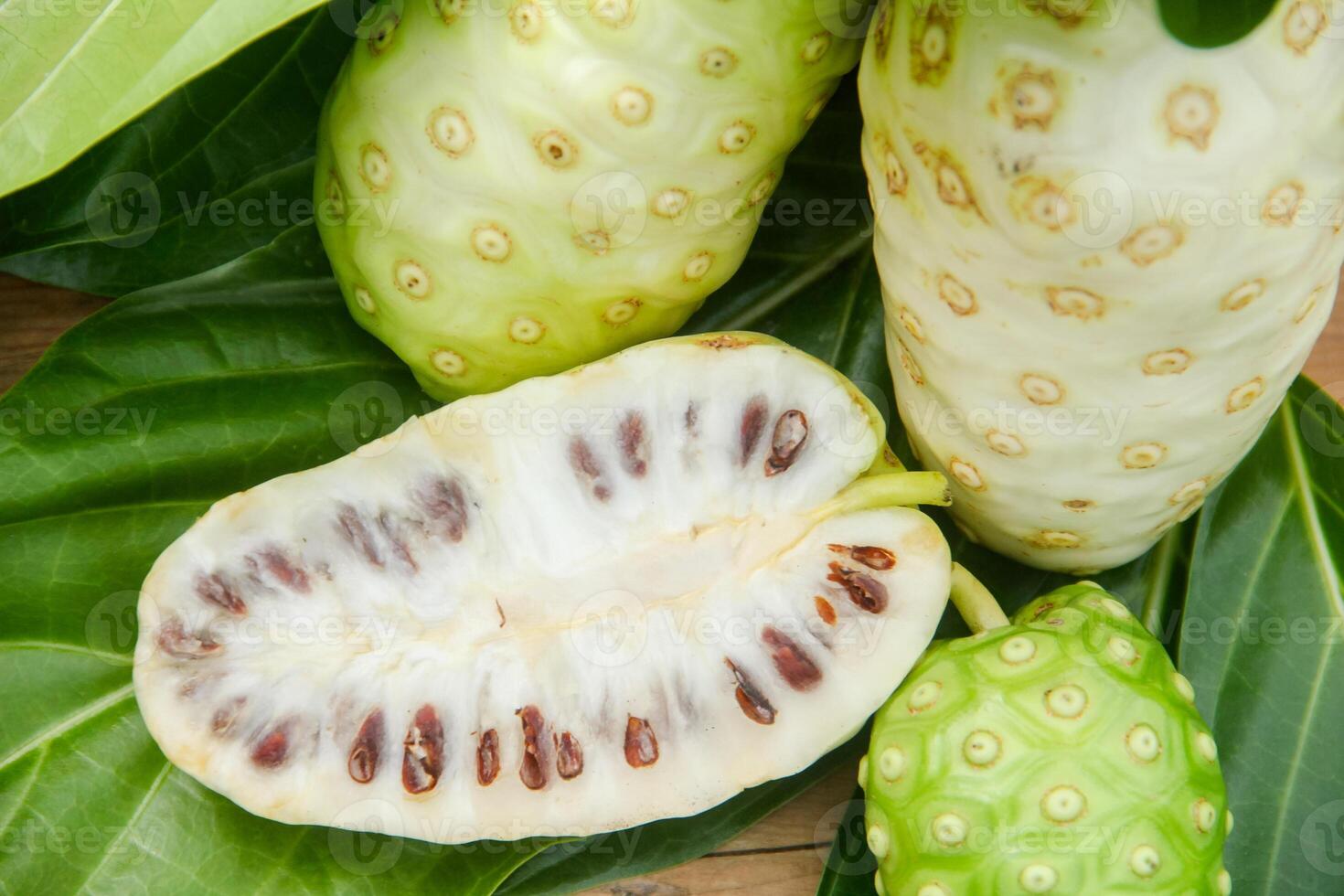 Noni fruit or Morinda citrifolia sliced and decorated with fruit and leaves on a natural background photo