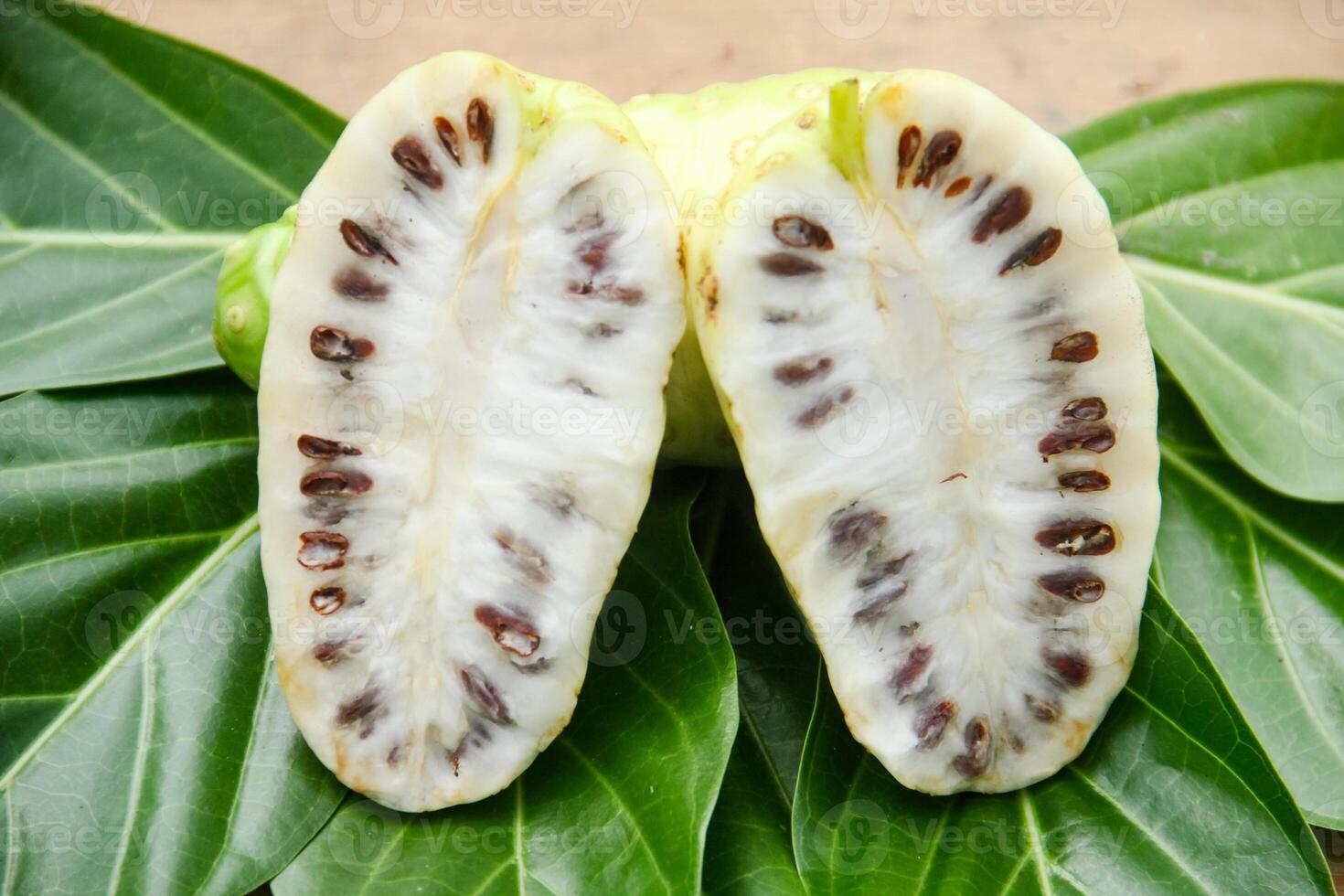 Noni fruit or Morinda citrifolia sliced and decorated with fruit and leaves on a natural background photo