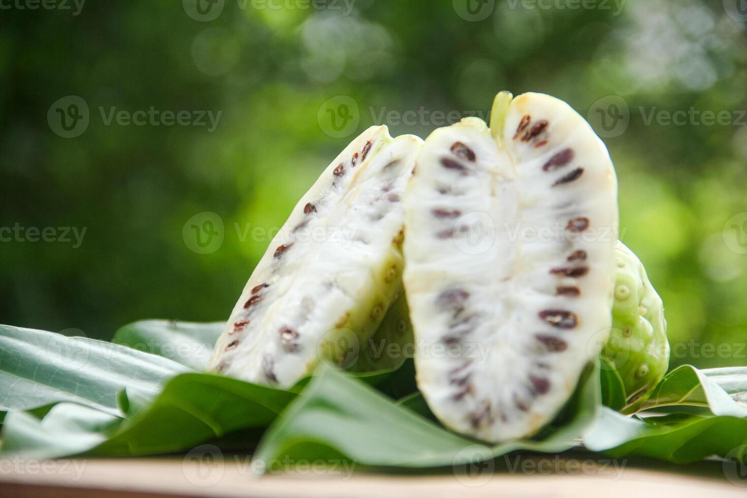 Noni fruit or Morinda citrifolia sliced and decorated with fruit and leaves on a natural background photo