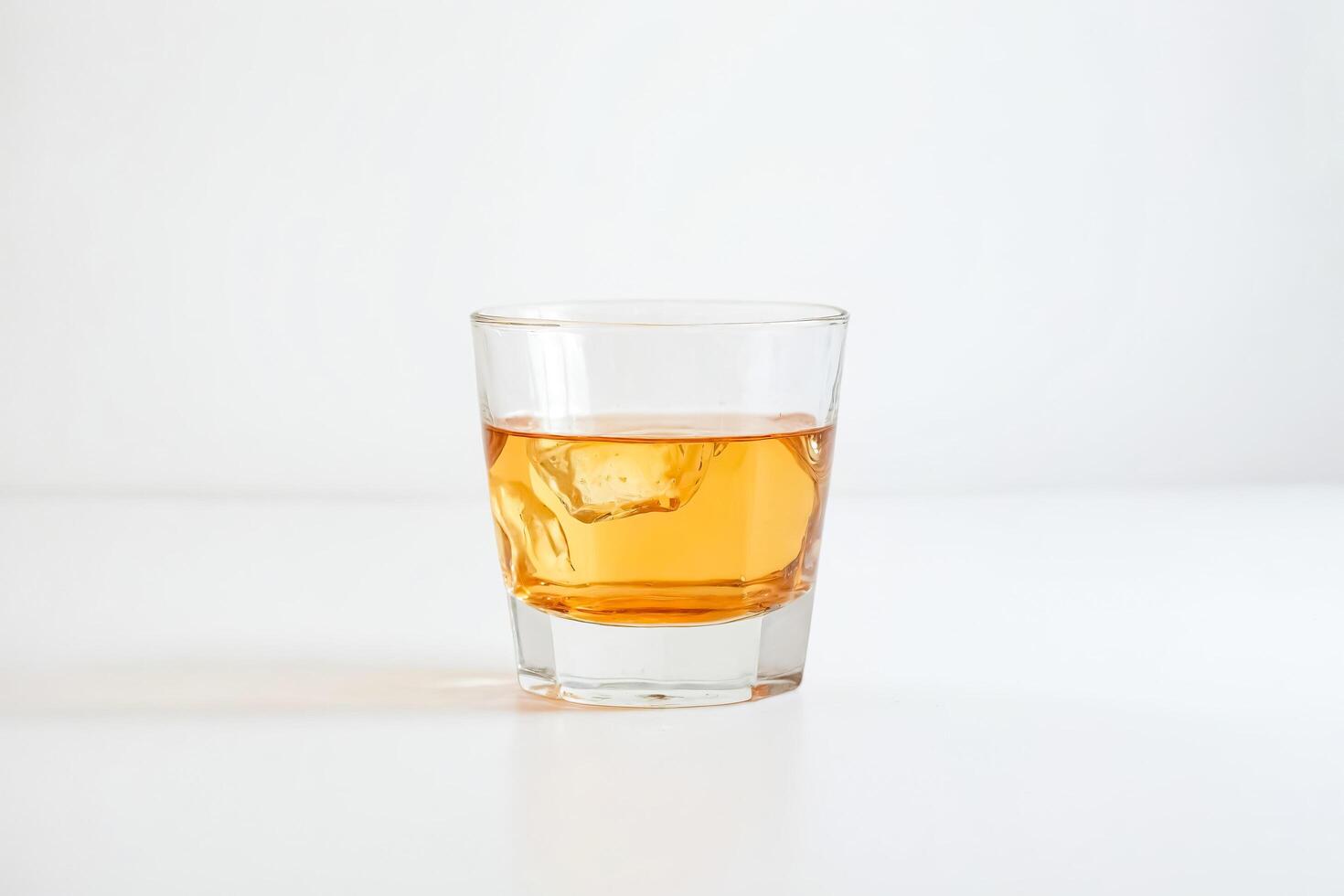 Single Glass of Whiskey with Ice on White Background photo