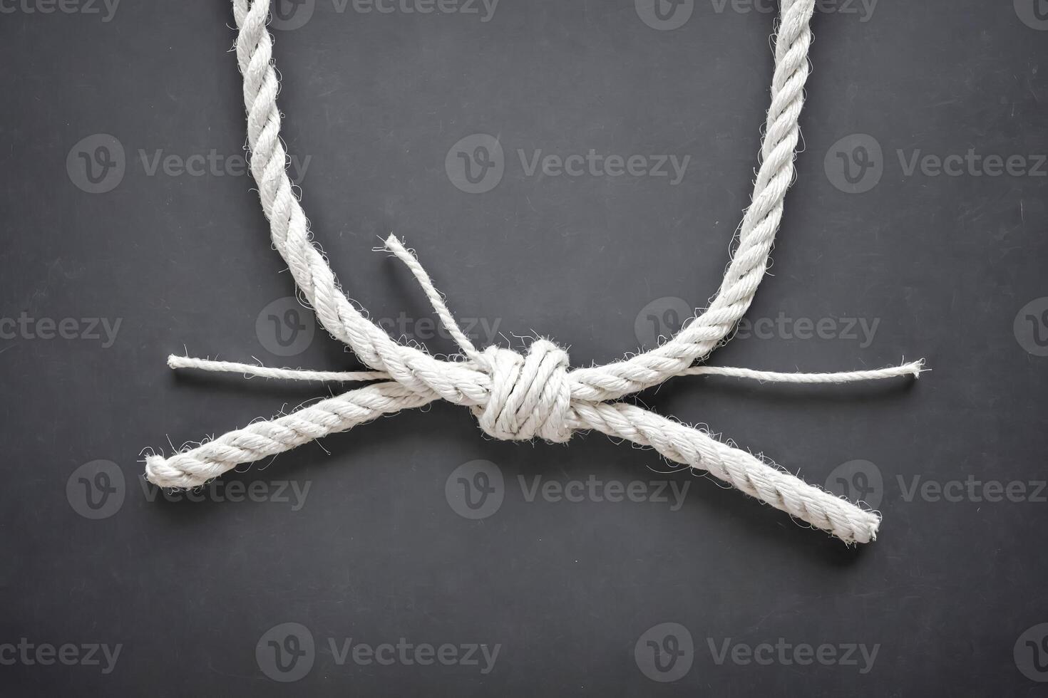 White Rope Tied in a Knot on a Gray Background photo