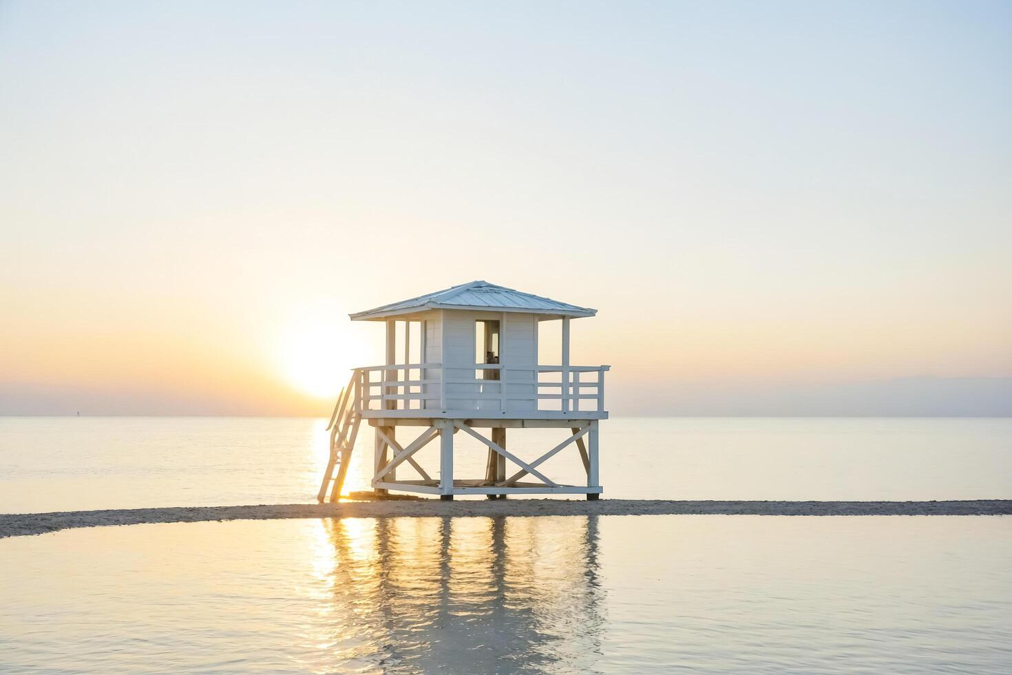 White Lifeguard Stand on Sandy Beach at Sunset photo