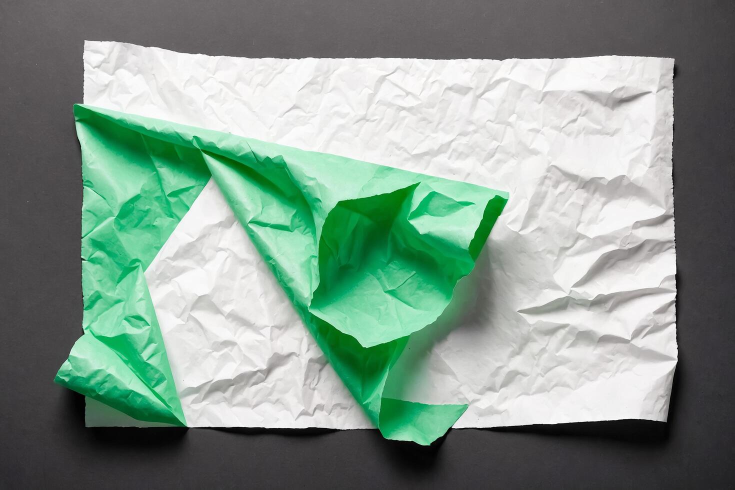 Crumpled Green and White Paper on Black Background photo