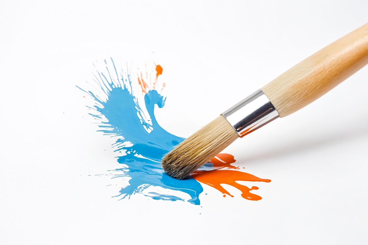 Paintbrush Making a Splash of Blue and Orange Paint photo