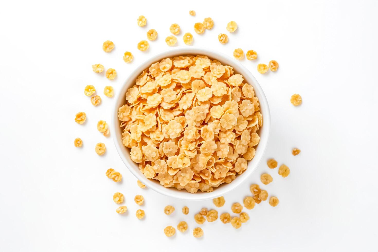 Bowl of corn flakes with scattered flakes around photo