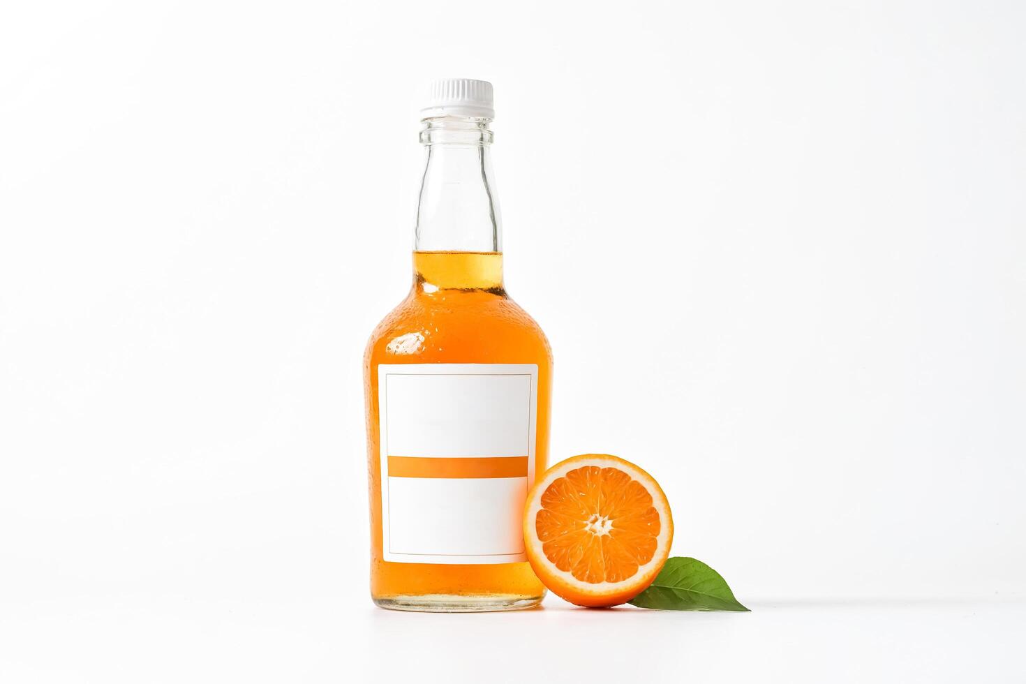 Glass Bottle of Orange Juice with Orange Slice and Leaf on White Background photo
