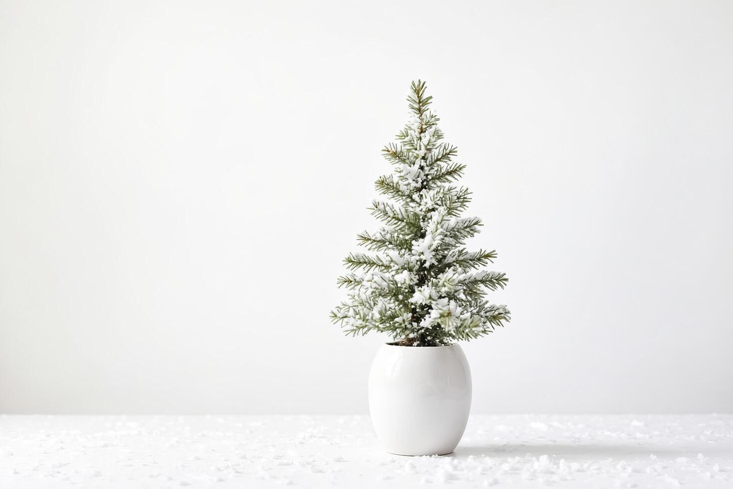 Small snow-covered Christmas tree in white pot photo