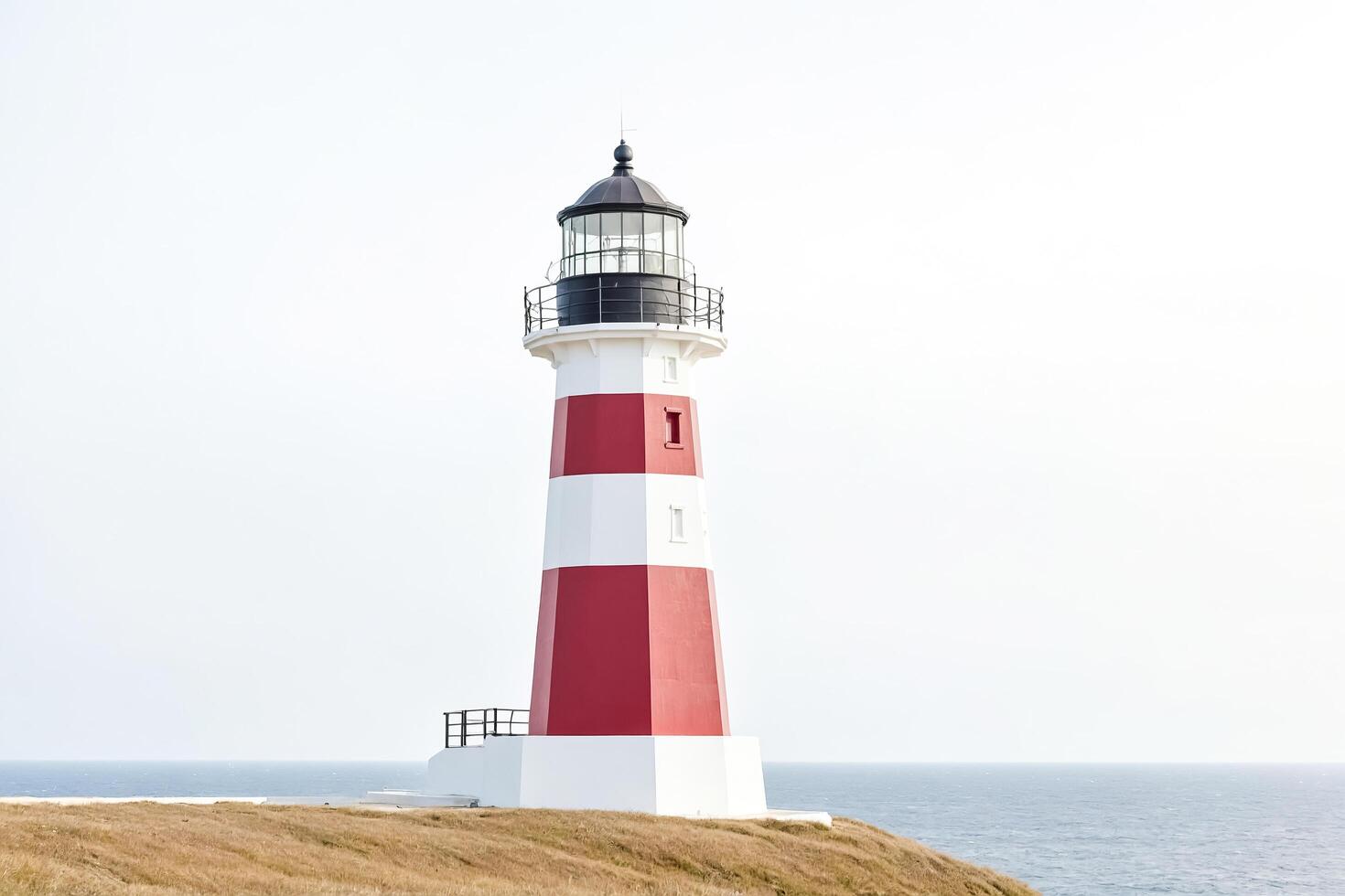 Red and White Lighthouse on a Cliff Overlooking the Ocean photo