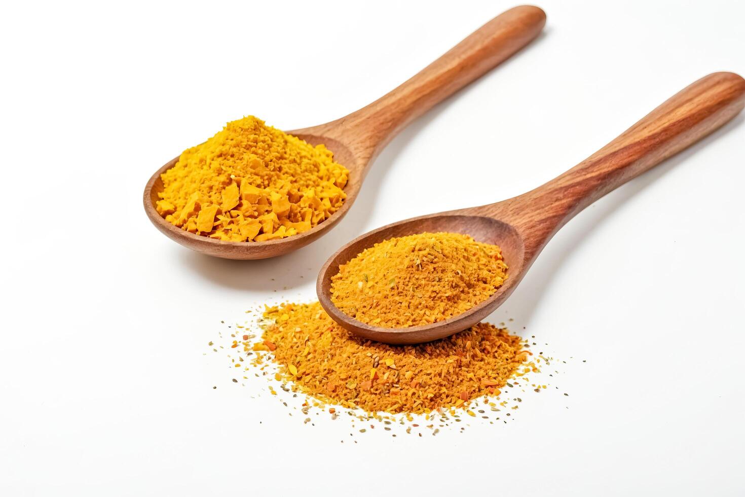 Two wooden spoons filled with yellow spices on a white background photo
