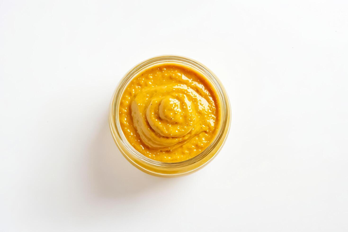 Close up of a small glass jar of mustard on white background photo