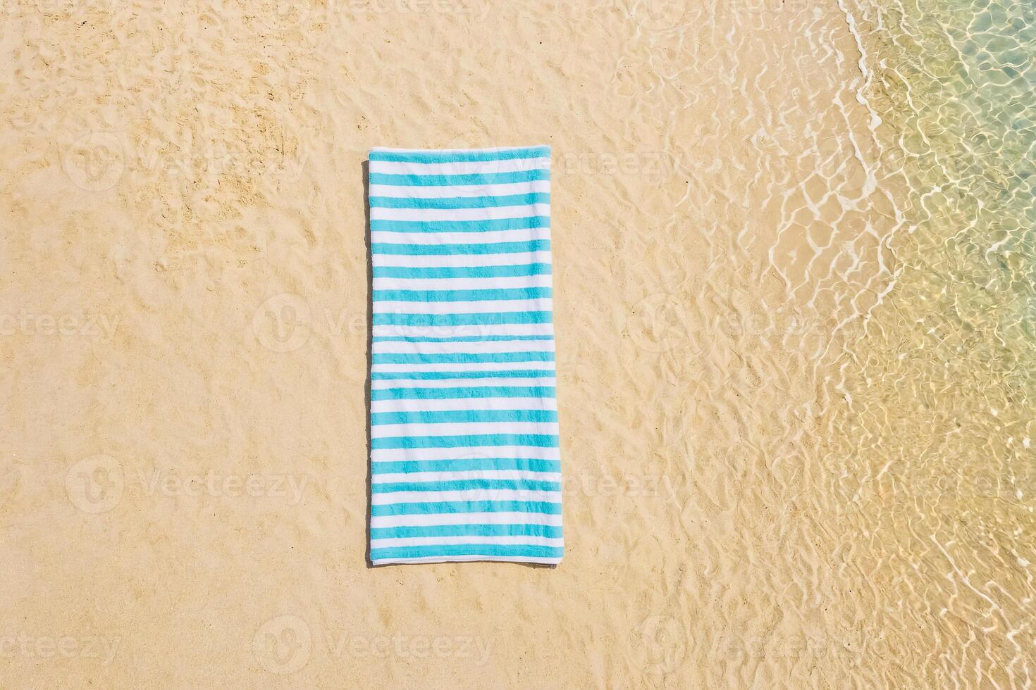 Blue and White Striped Beach Towel on Sandy Beach photo