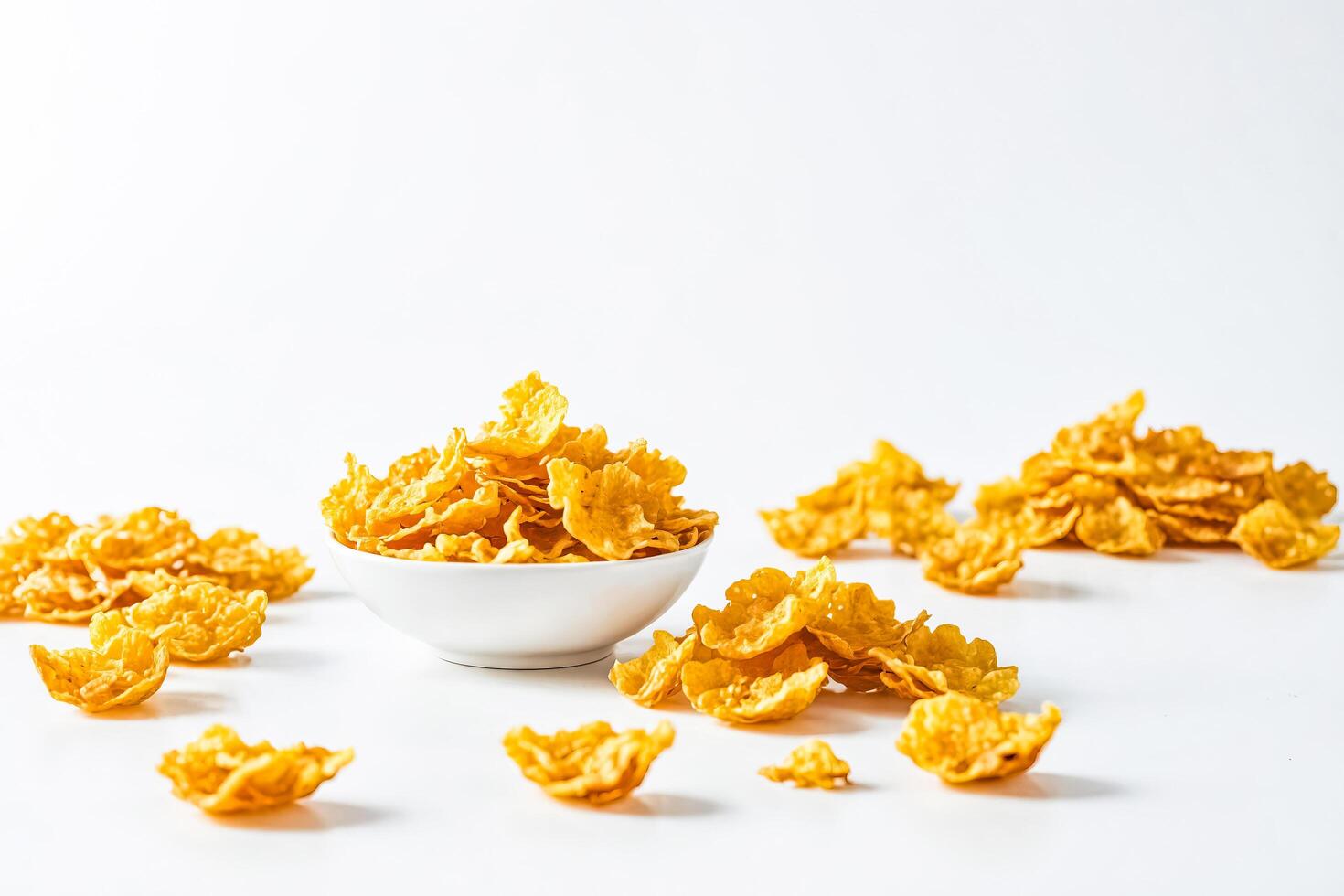 Cornflakes spilling out of a bowl on a white background photo