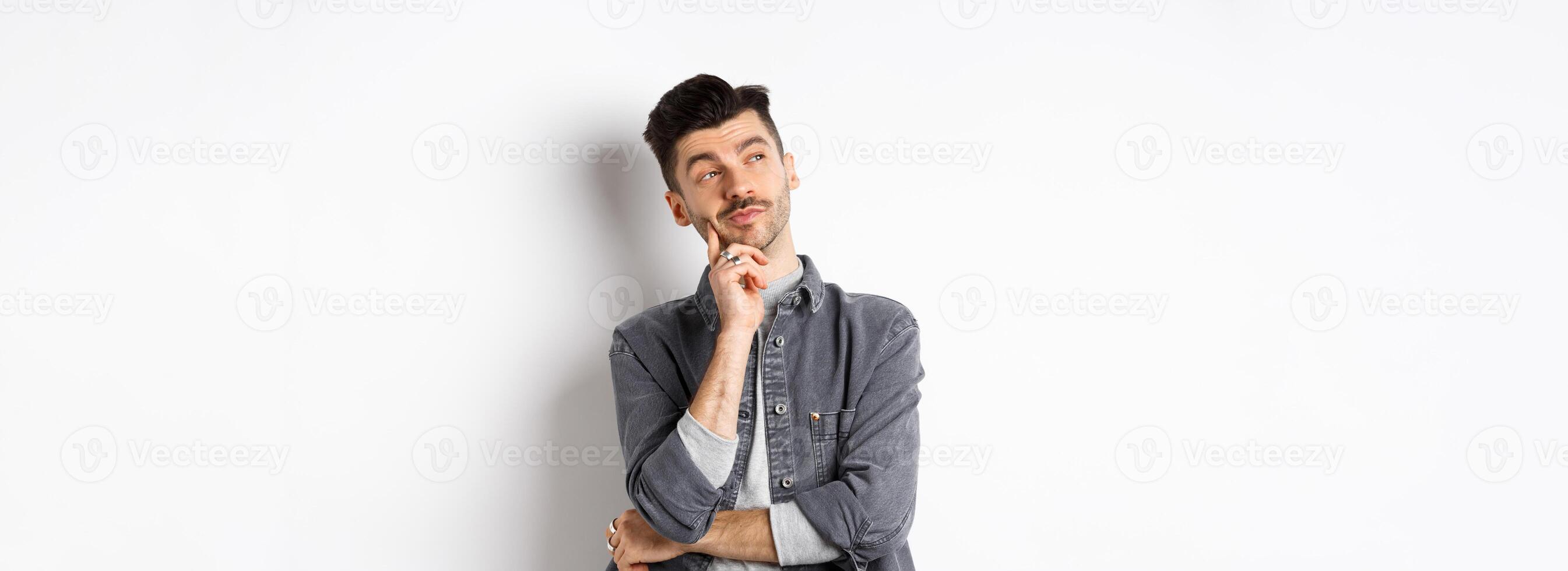 Thoughtful handsome man looking aside pensive, making choice, standing on white background photo