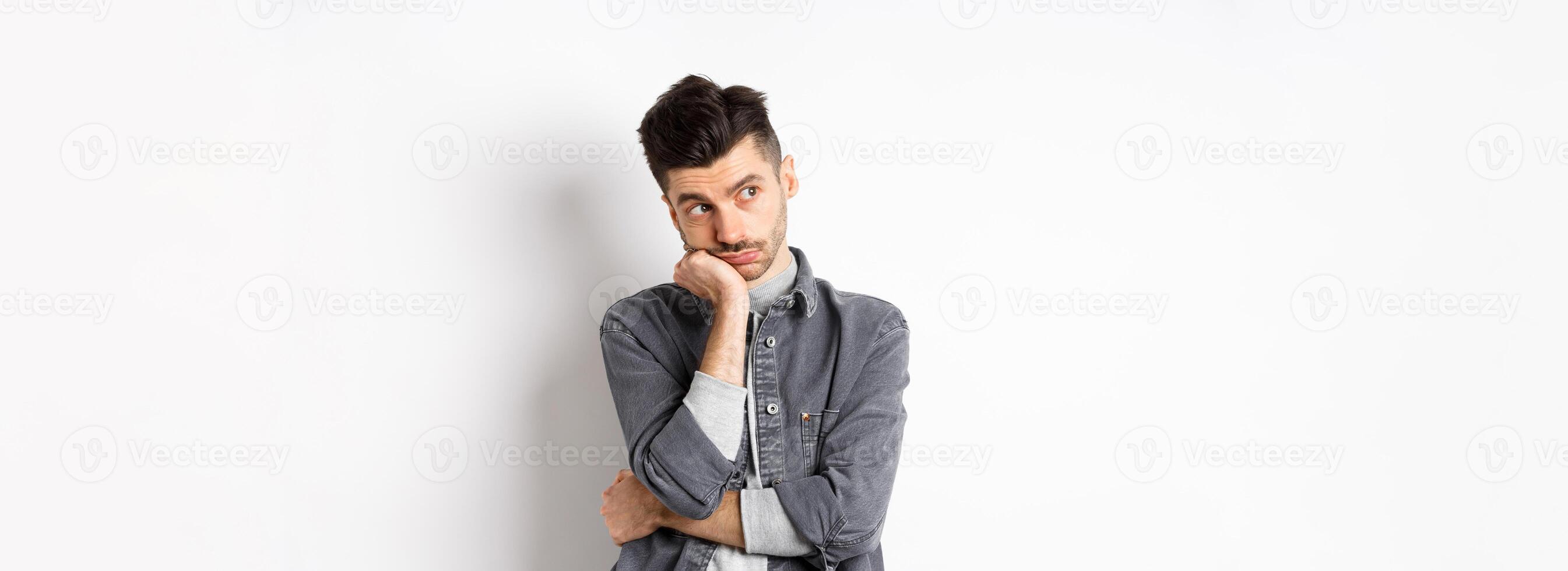 Gloomy thoughtful man looking aside, thinking or space out, staring at empty space bored, standing on white background photo