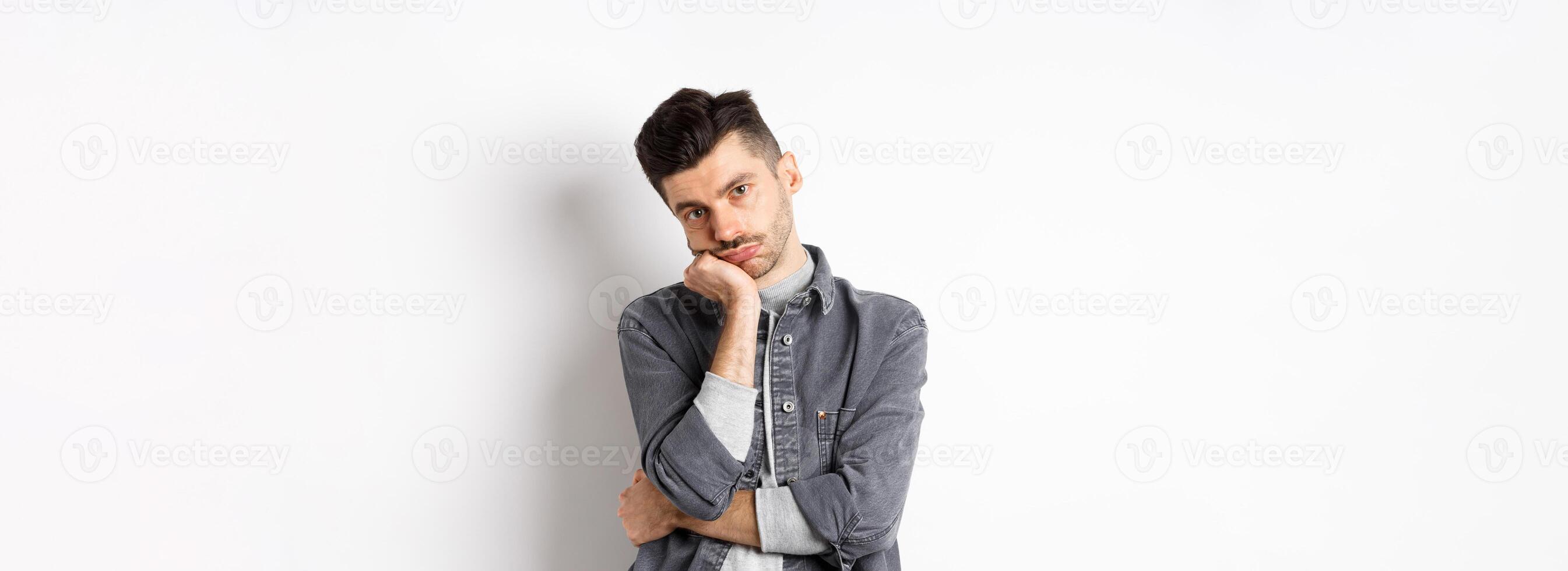 Bored and reluctant stylish guy look at camera without emotions, attend boring meeting, standing on white background photo