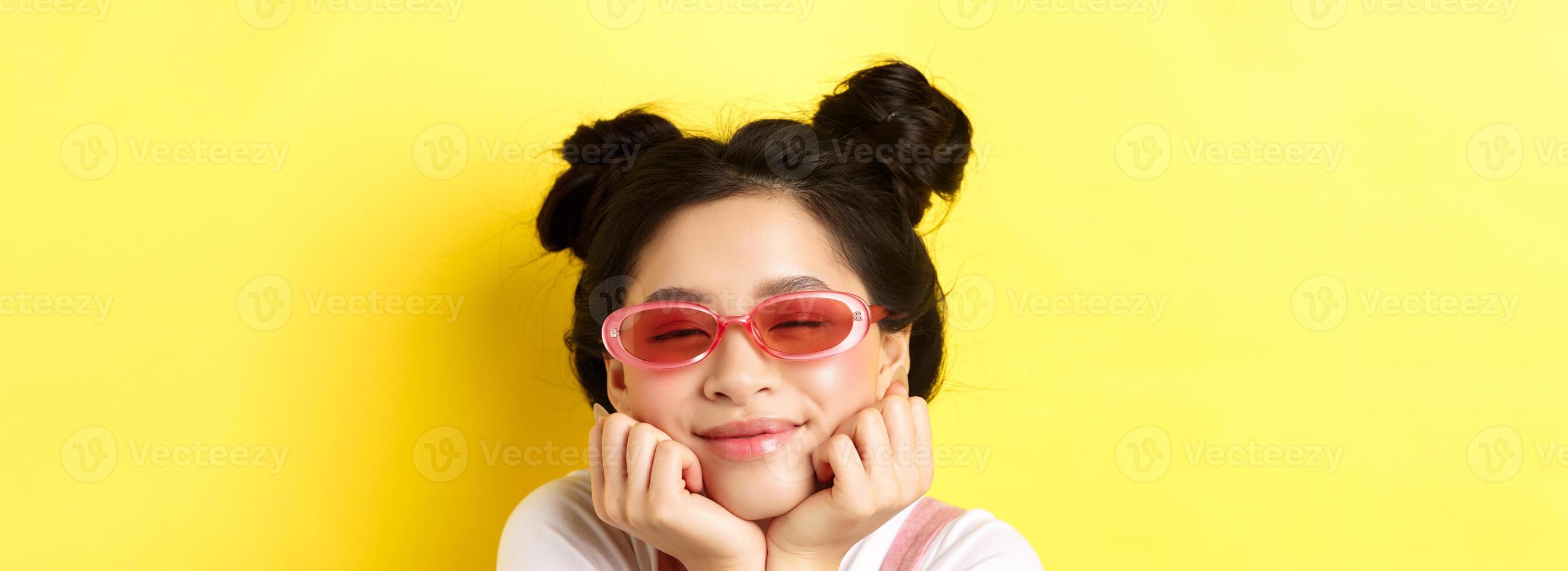 Summer fashion concept. Dreamy asian girl with romantic face expression, daydreaming or imaging something beautiful with closed eyes and happy smile, wearing sunglasses photo