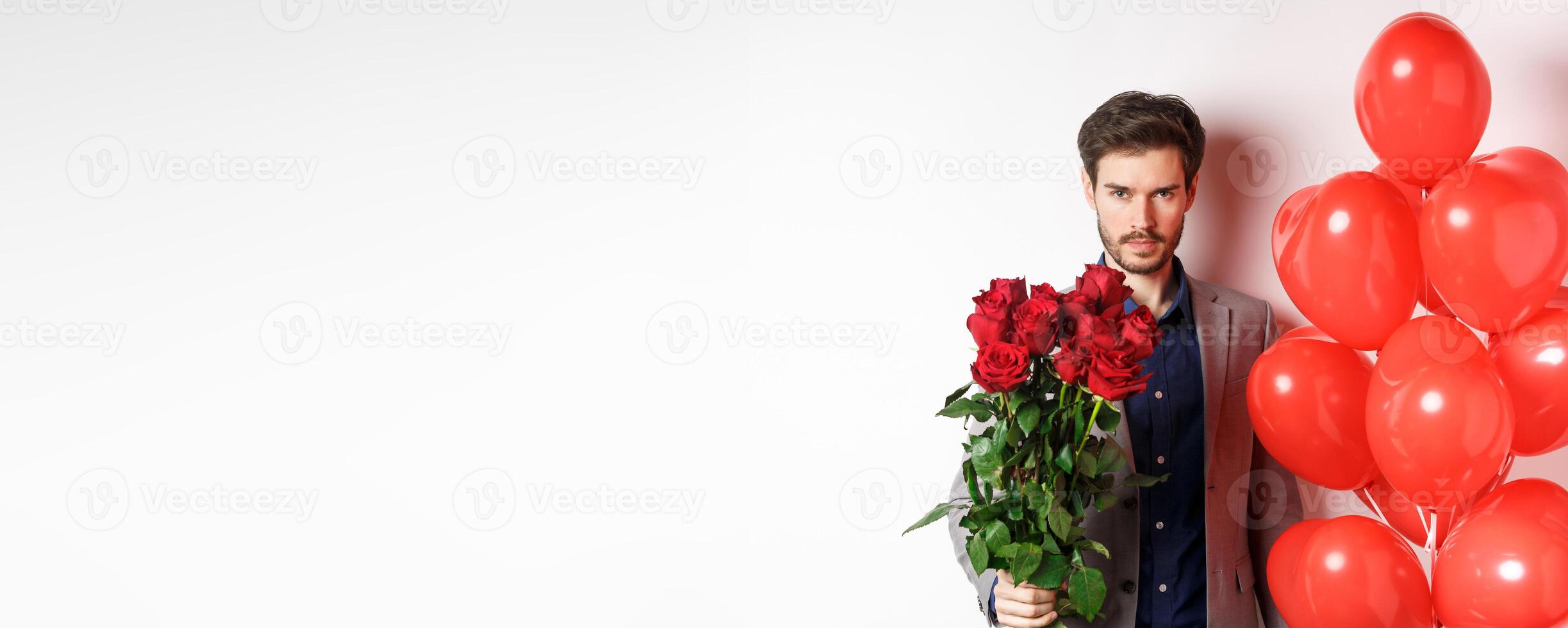 Macho man going on romantic date, looking confident at camera, holding gifts for lover on Valentines day, standing with heart balloons and red roses, white background photo