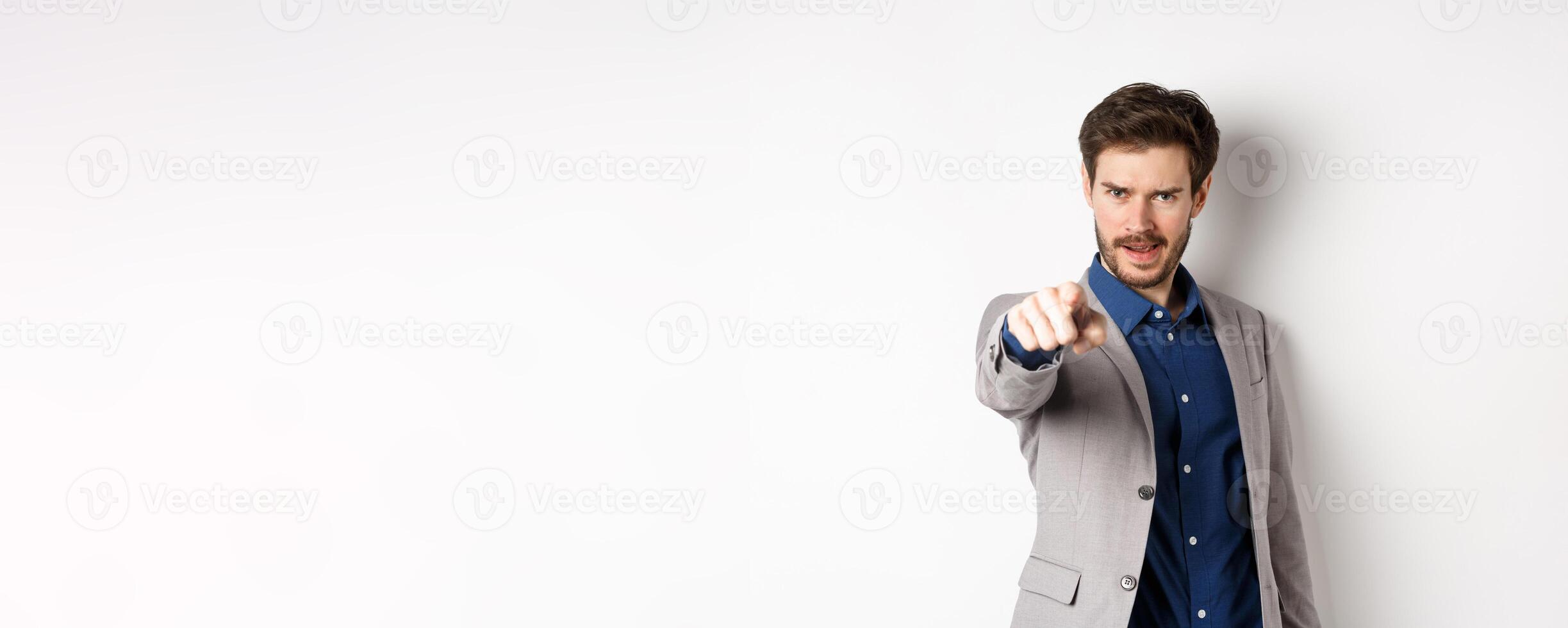 Confident and motivated businessman in suit need you, pointing finger at camera with encouraging face, choosing person, standing on white background photo