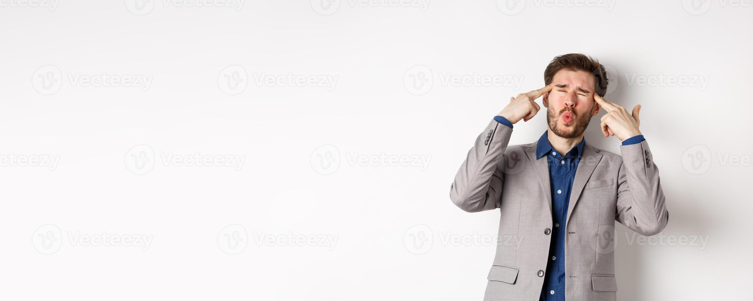 Distressed and tensed businessman pointing at head and complaining, feeling annoyed with situation blowing his mind, standing bothered on white background photo