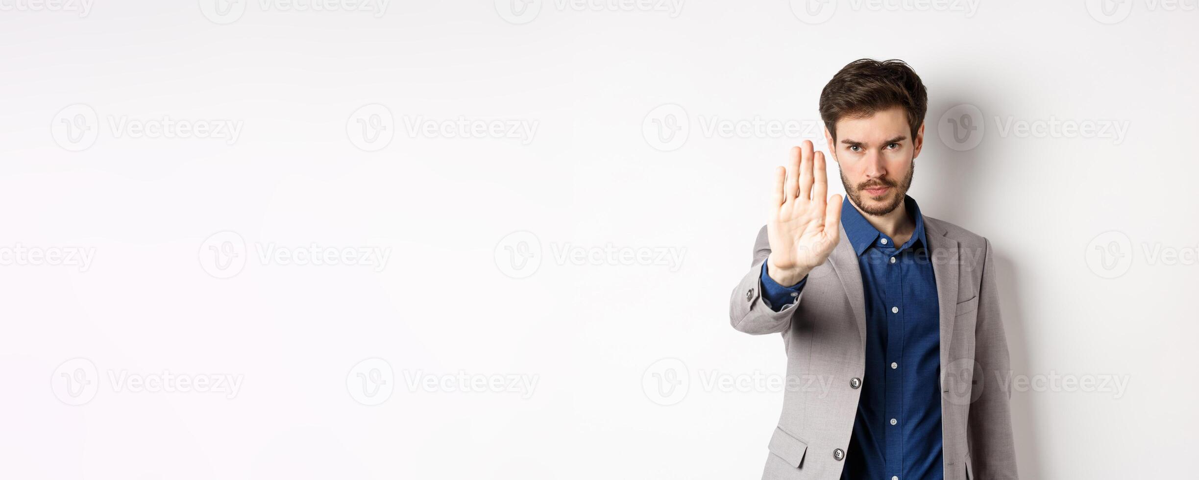 Hold right there. Serious businessman in suit stretch out hand and tell to stop, frowning and look confident, disapprove action, prohibit something bad, standing on white background photo