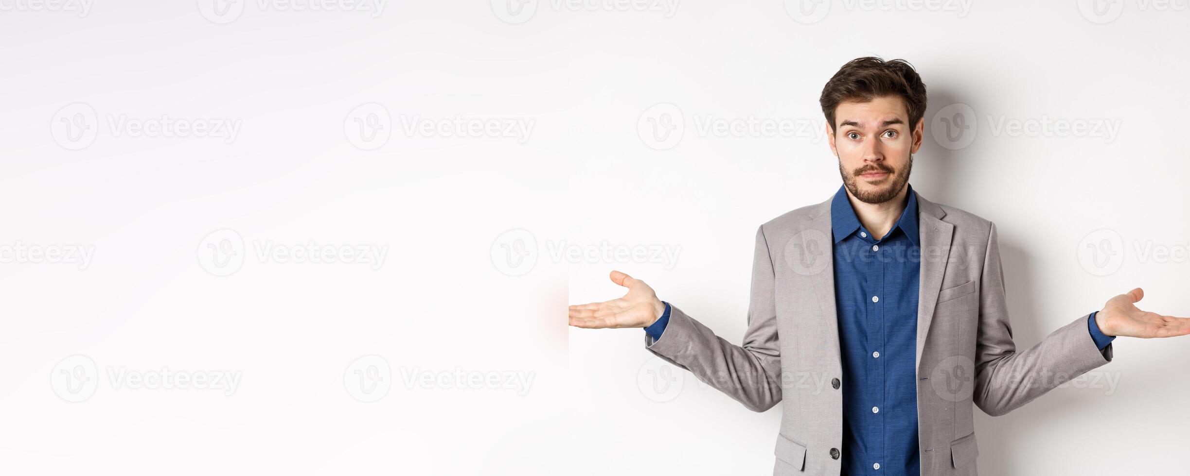 Dont know. Confused businessman spread hands sideways and look clueless, cant help, have no idea, standing on white background in suit photo
