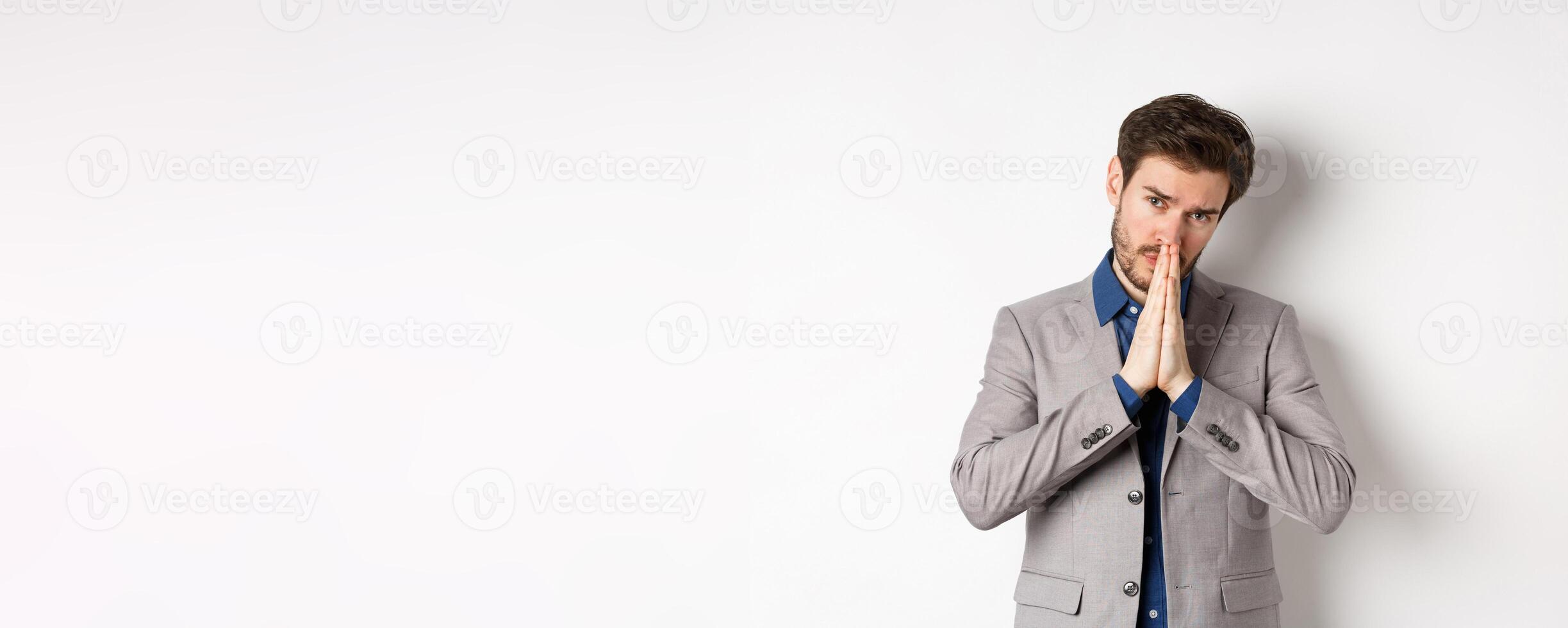 Please help. Pleading man in suit asking for favour, begging you, standing on white background photo