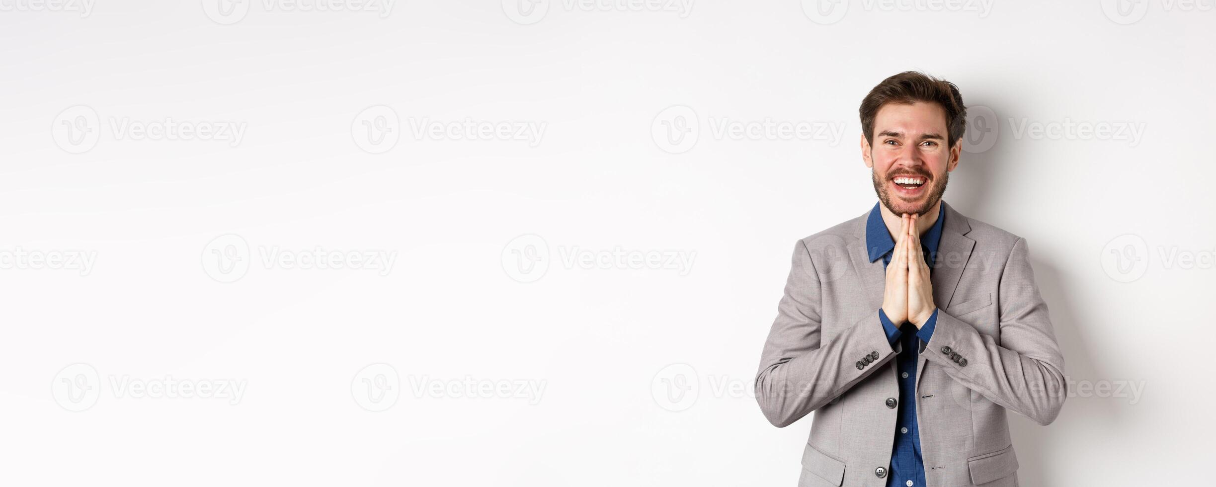 Happy caucasian businessman say thank you, smiling and laughing with hands showing namaste sign, express gratitude, standing on white background photo