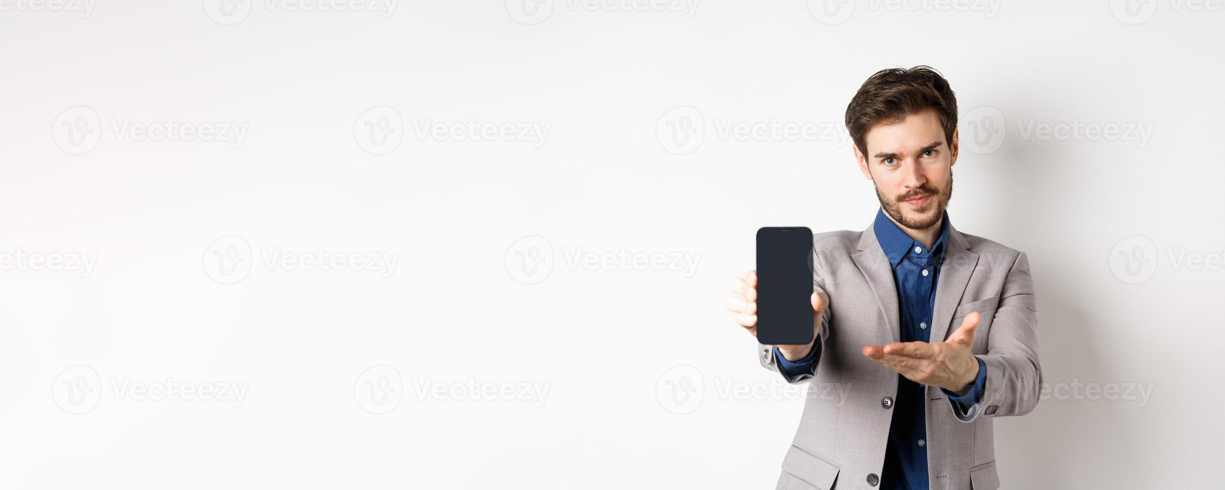 E-commerce and online shopping concept. Man demonstrated empty smartphone screen to you, showing phone display to introduce something, standing on white background photo