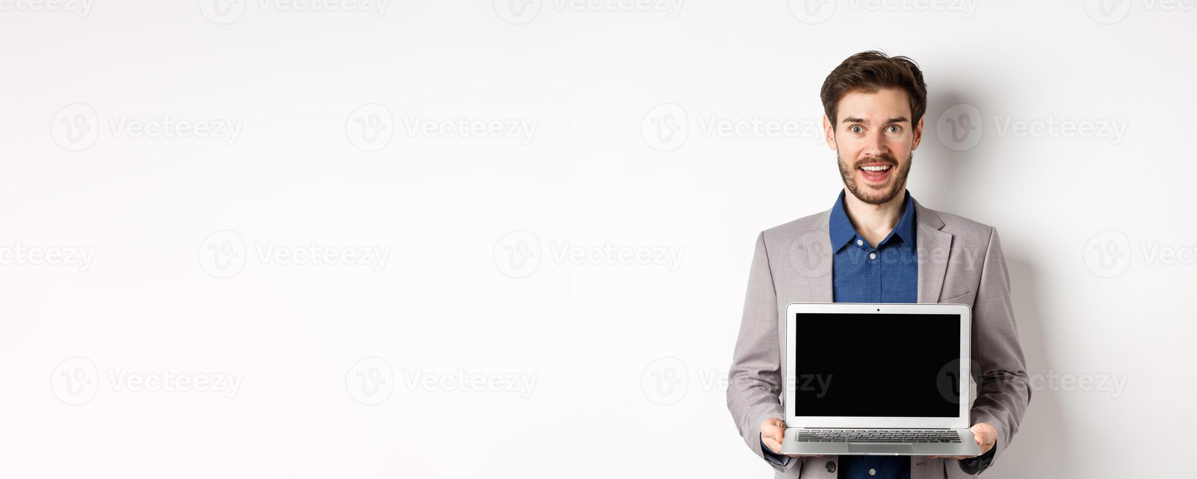 Handsome caucasian businessman in suit showing empty laptop screen, demonstrate promo, standing on white background photo