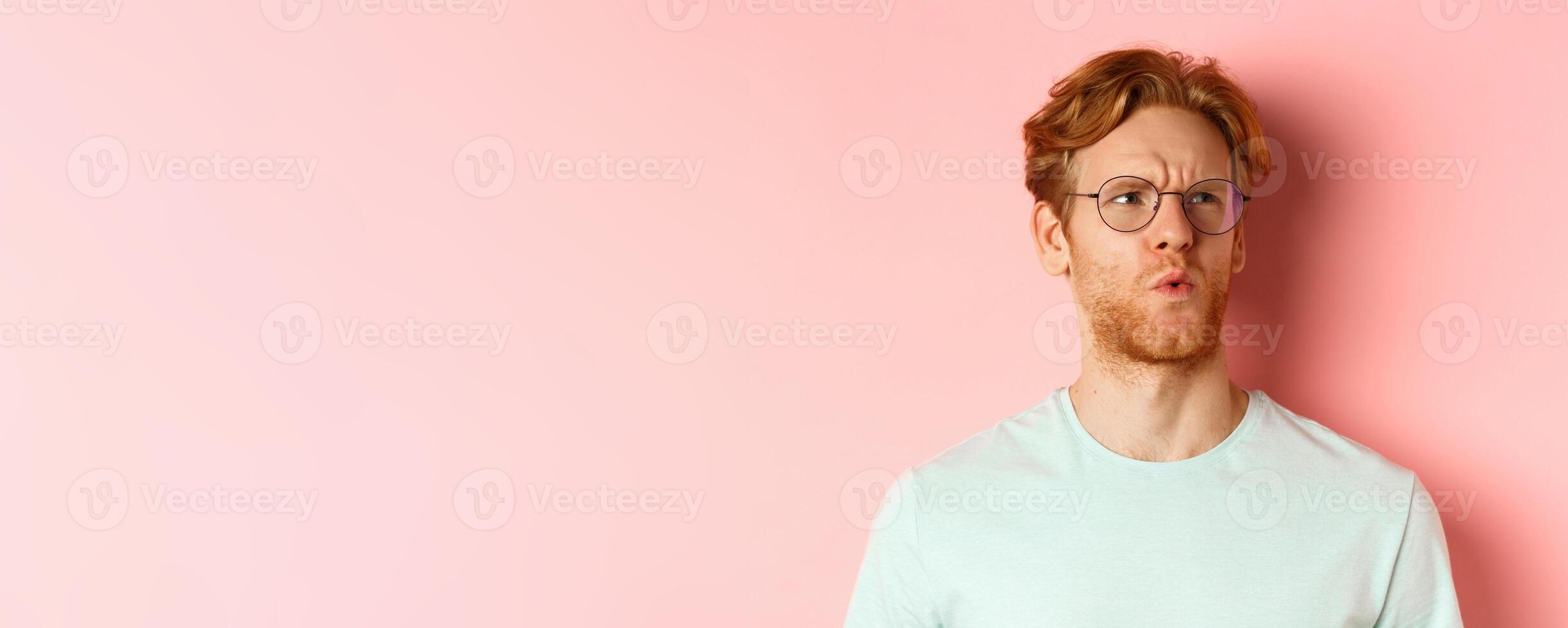 Ouch thats bad. Face of redhead man showing pity and feeling sorry for someone, frowning and looking with compassion, standing over pink background photo