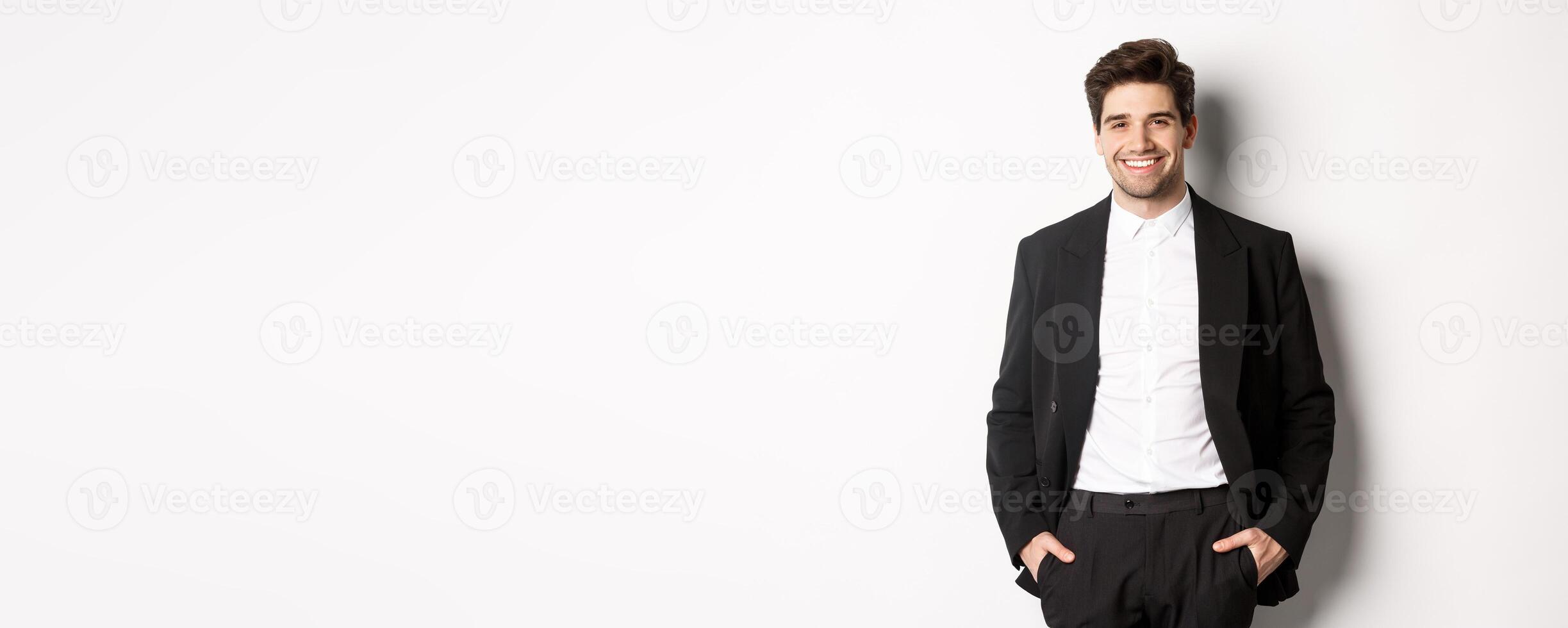 Image of handsome caucasian man in party suit, smiling pleased, attend formal event, standing over white background photo